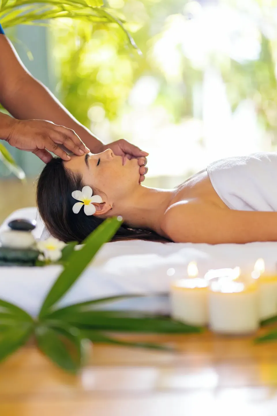 A close-up shows a facial massage with candles and tropical greenery at Carlisle Bay.