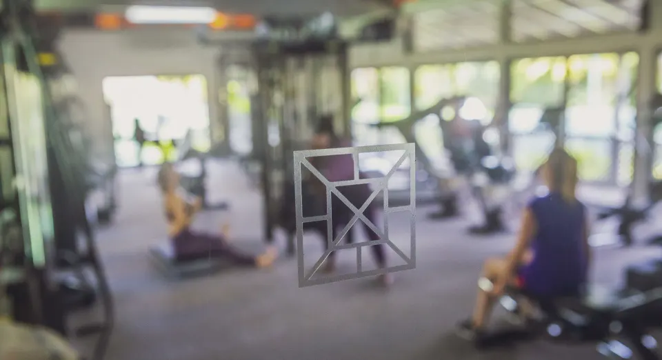 Blurred gym scene with people exercising behind glass at Carlisle Bay.