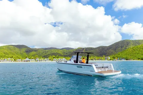 A motorboat cruises across the bay with Carlisle Bay resort in the background.