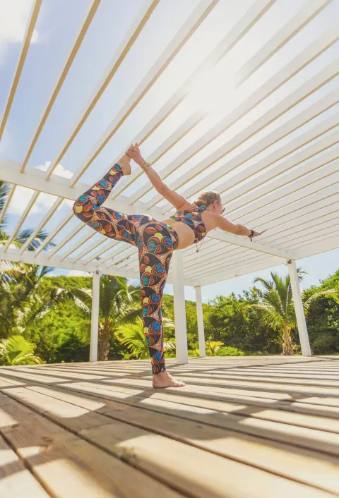 A guest practices yoga on a sunlit deck at Carlisle Bay.