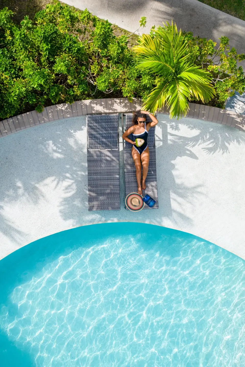 Overhead view of a guest on a lounger beside a curved pool at Carlisle Bay.