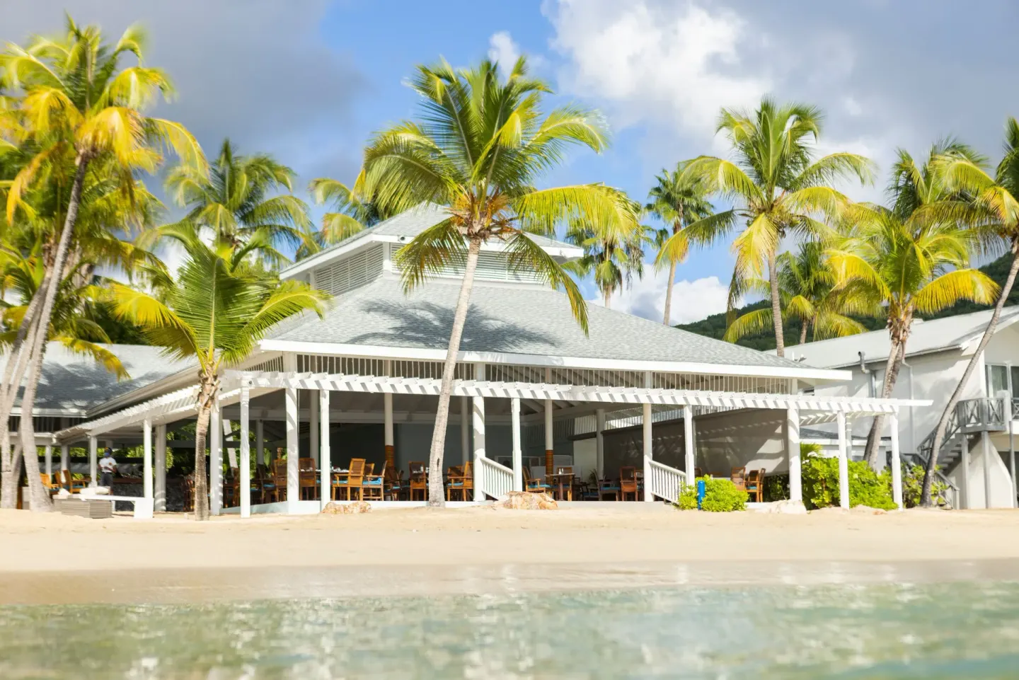 Beachfront pavilion with palm trees and shallow water in front at Carlisle Bay.