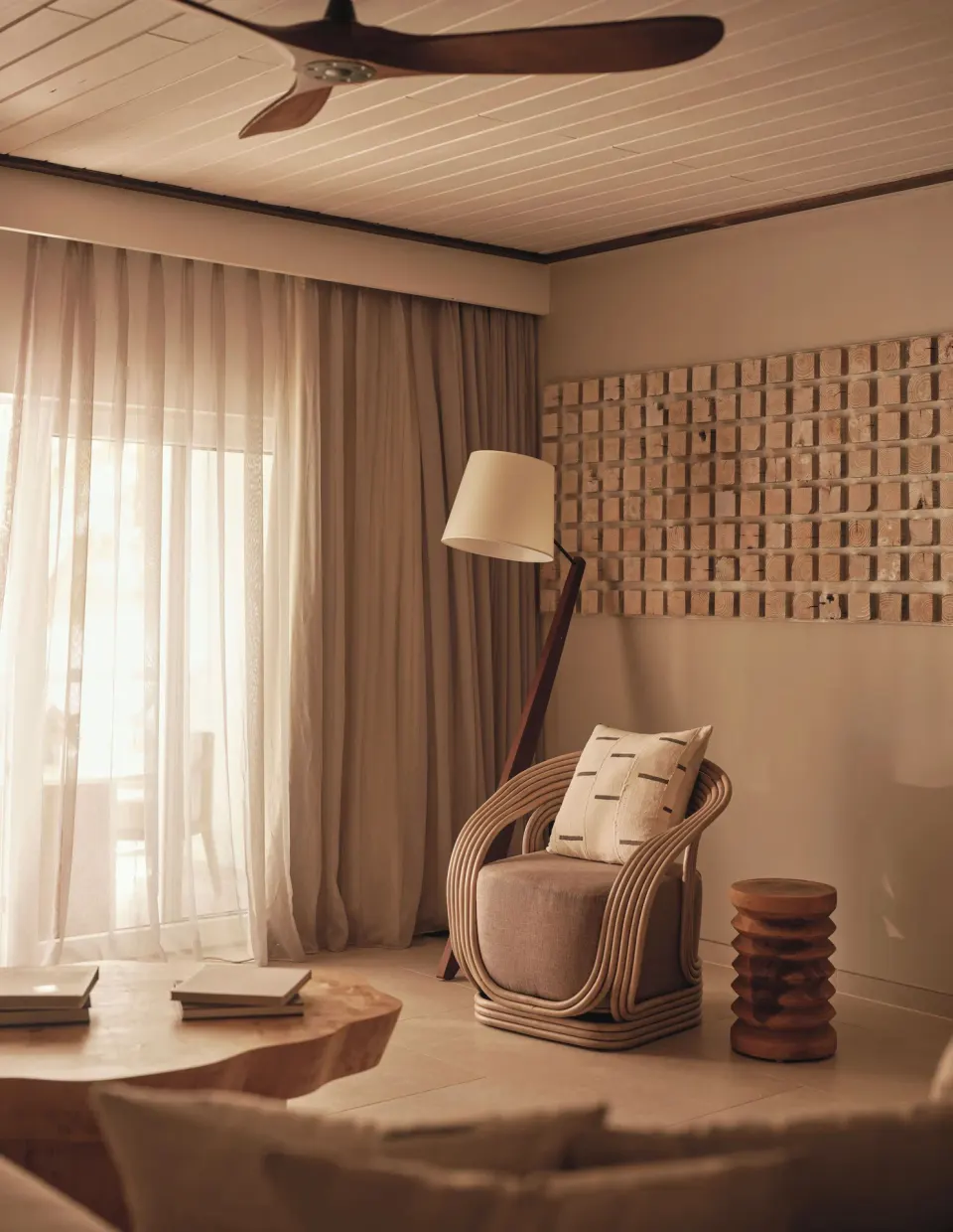 Bay Suite lounge corner with rattan chair and sheer curtains at Carlisle Bay.