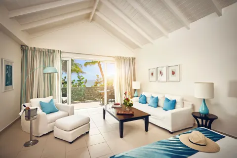 Beach balcony suite living area at Carlisle Bay with white seating, vaulted ceiling and balcony doors.