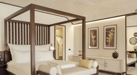 Garden Suite bedroom with four-poster bed and bench at Carlisle Bay.