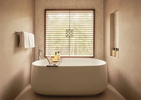 Garden Suite bathroom with freestanding tub and shuttered window at Carlisle Bay.