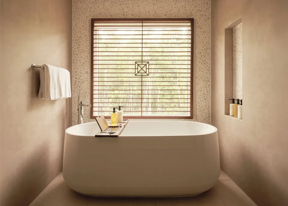 Garden Suite bathroom with freestanding tub and shuttered window at Carlisle Bay.