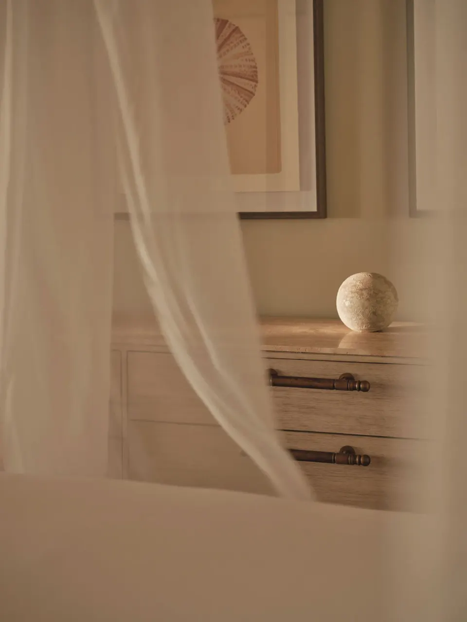 Sheer bed drape and bedside chest in an Ocean Suite at Carlisle Bay.