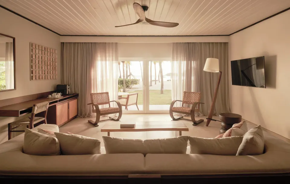 Ocean Suite living room with sofa, chairs, and terrace doors at Carlisle Bay.