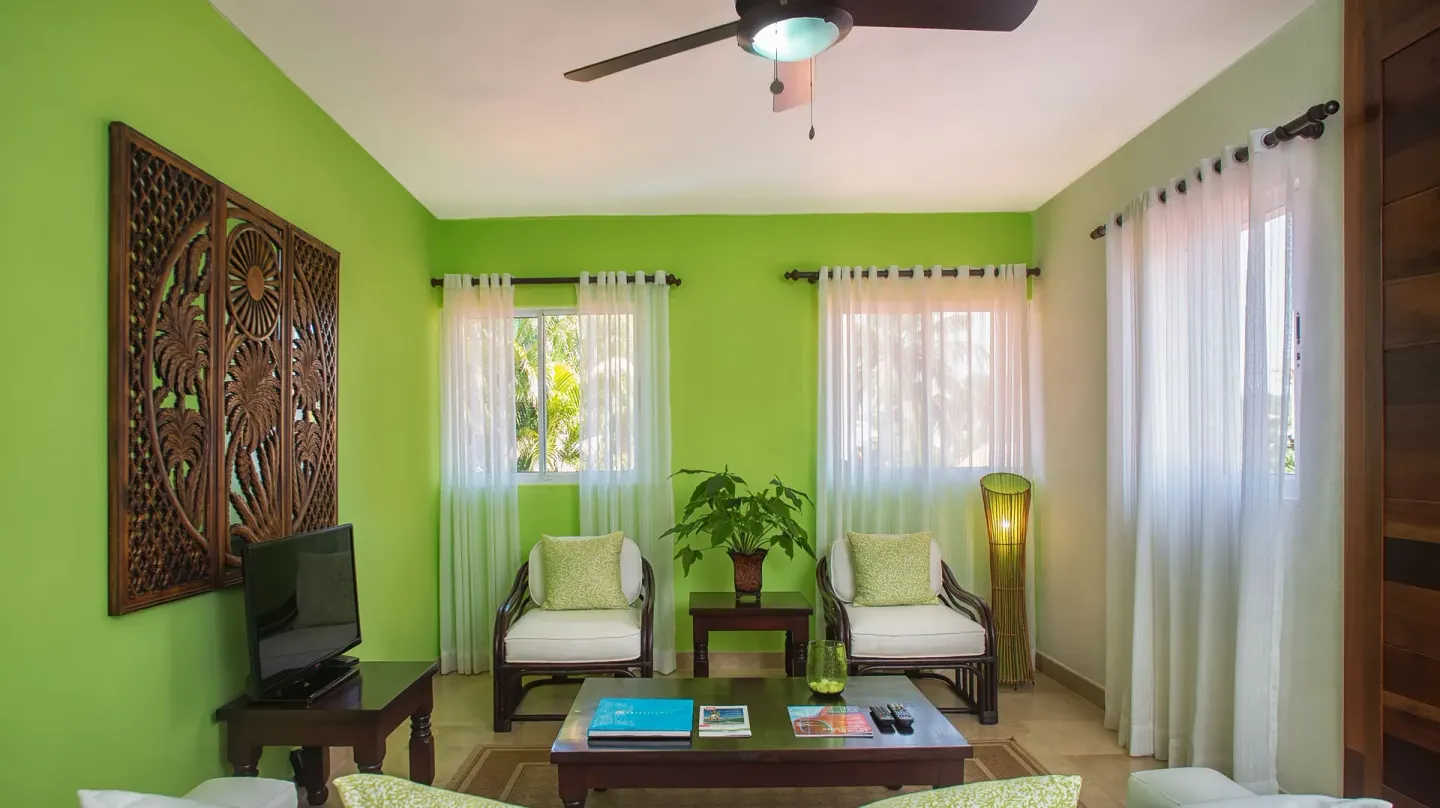 Green-walled sitting room with chairs and sheer curtains at Casa de Campo Resort and Villas and Villas and Villas.