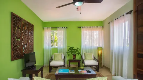 Green-walled sitting room with chairs and sheer curtains at Casa de Campo Resort and Villas and Villas and Villas.