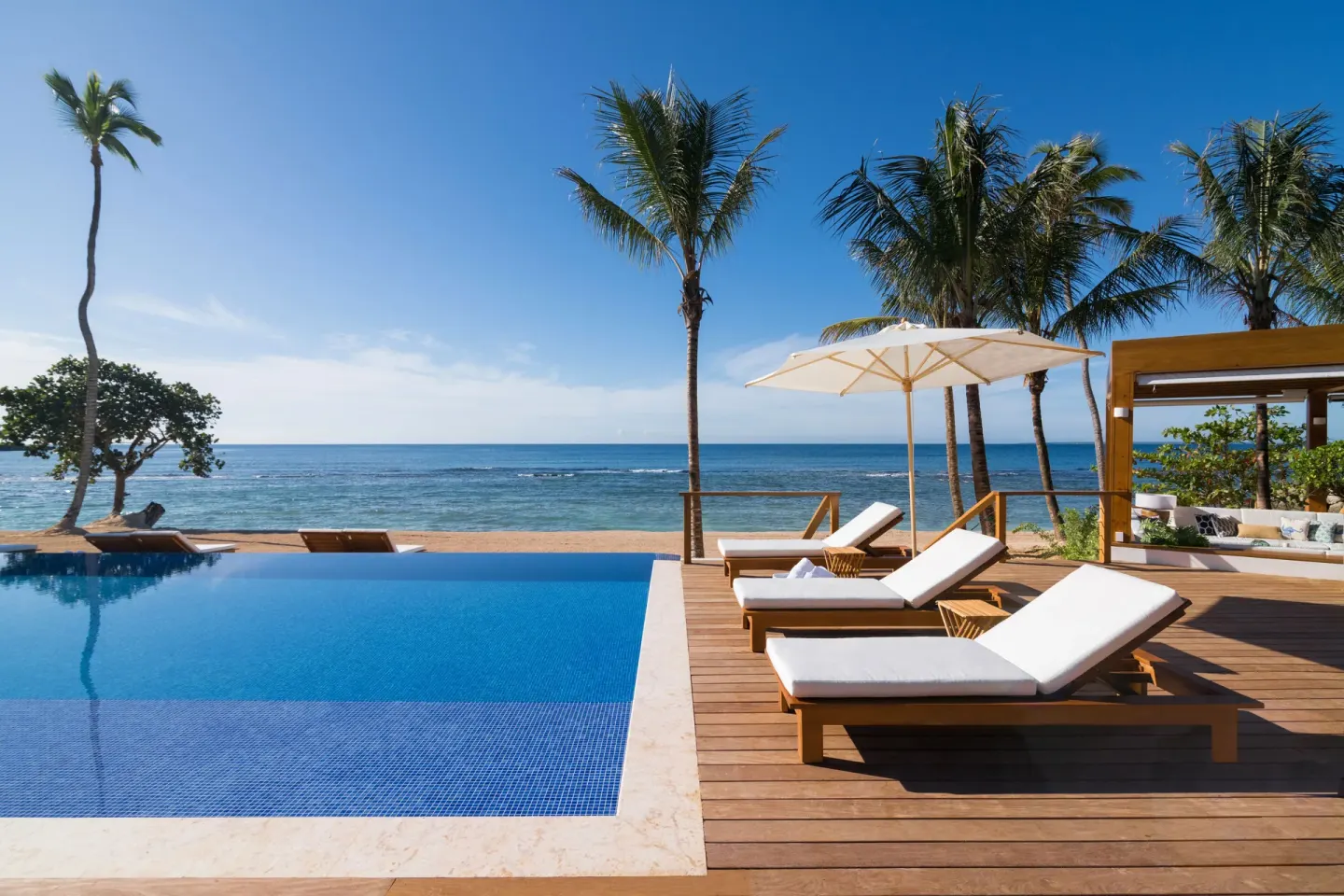 Infinity pool with beach loungers, palms, and ocean views at Casa de Campo Resort and Villas and Villas and Villas.