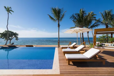 Infinity pool with beach loungers, palms, and ocean views at Casa de Campo Resort and Villas and Villas and Villas.