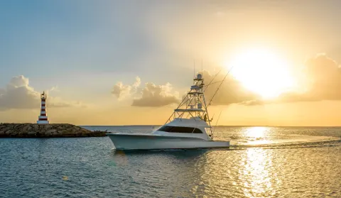A sportfishing boat passes a striped lighthouse near Casa de Campo Resort and Villas and Villas and Villas.