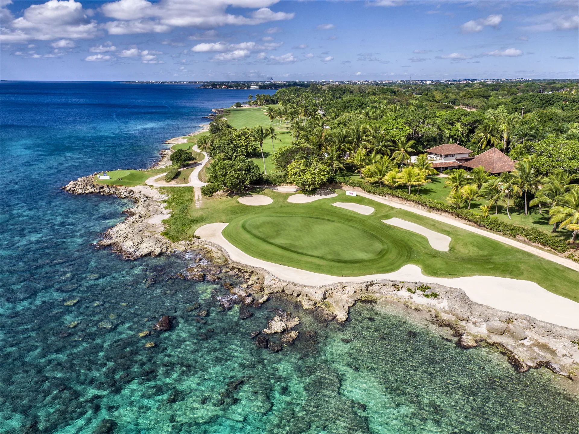Oceanfront golf green and bunkers beside blue water at Casa de Campo Resort and Villas.