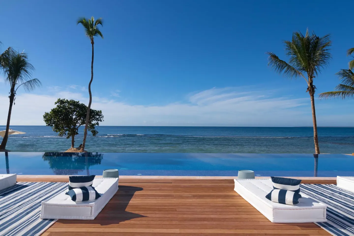 Infinity pool deck with ocean and palms at Casa de Campo Resort and Villas.