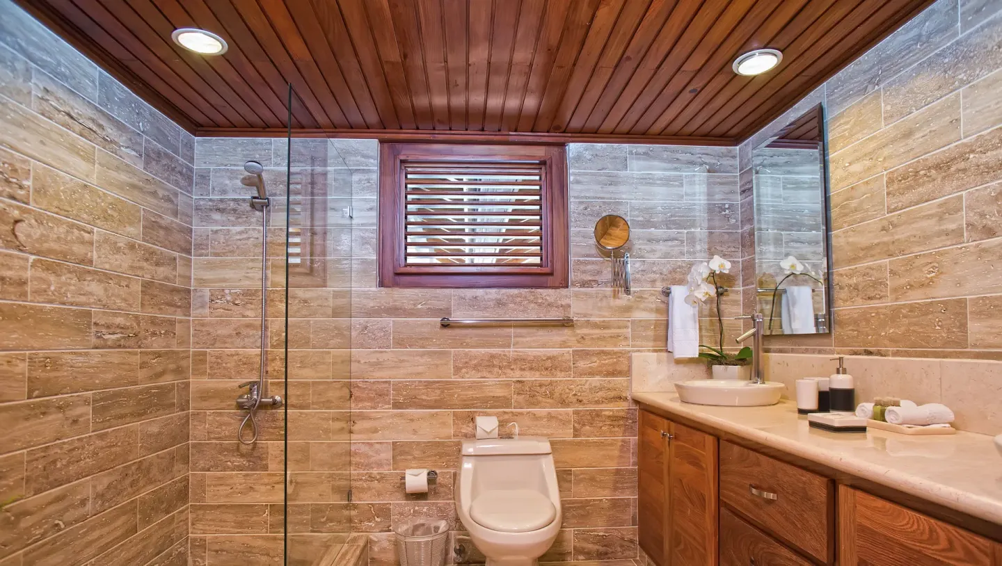 Stone-tiled bathroom with glass shower at Casa de Campo Resort and Villas.