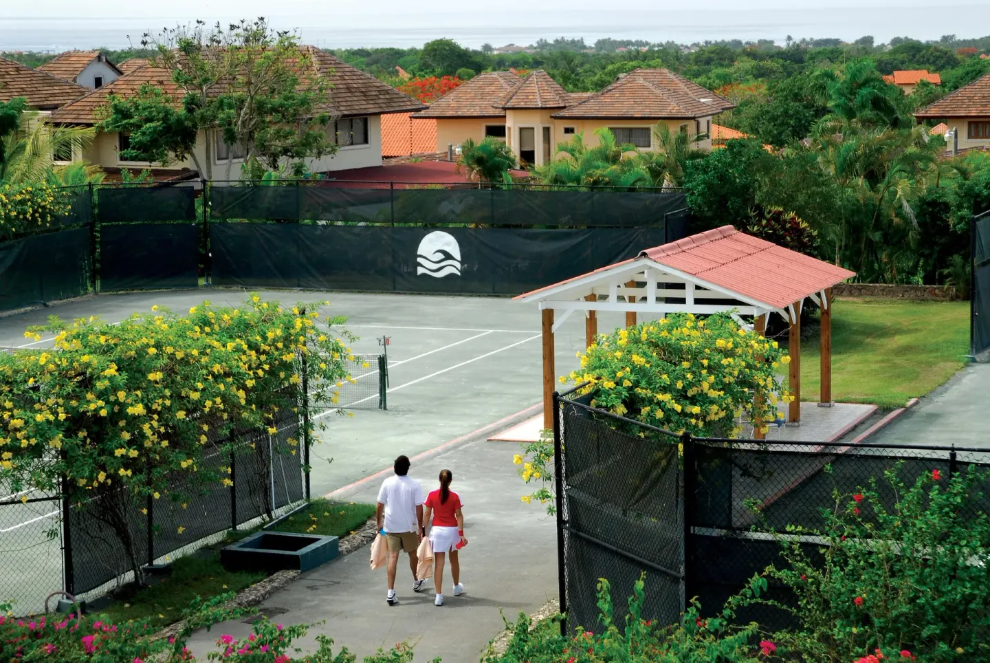 A couple walks toward tennis courts at Casa de Campo Resort and Villas.