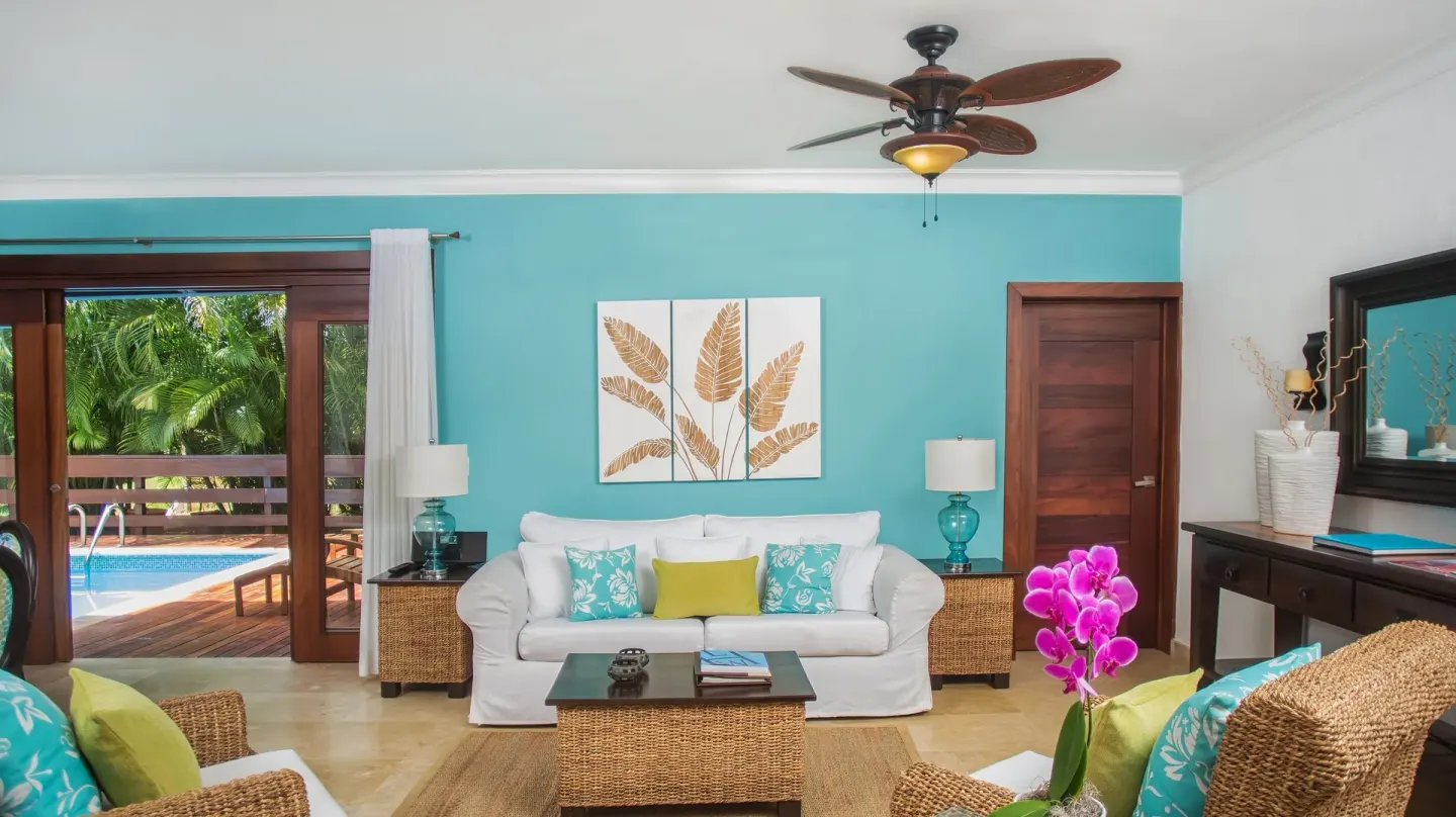 Living room with turquoise wall and doors to a pool deck at Casa de Campo Resort and Villas and Villas and Villas.