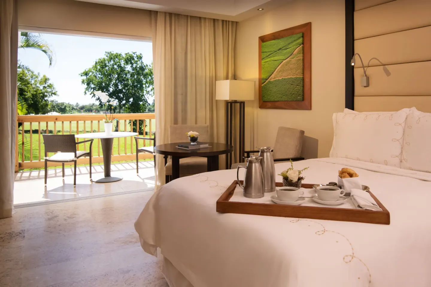 Elite Room king bed opening to a patio with golf course views at Casa de Campo Resort and Villas and Villas and Villas.