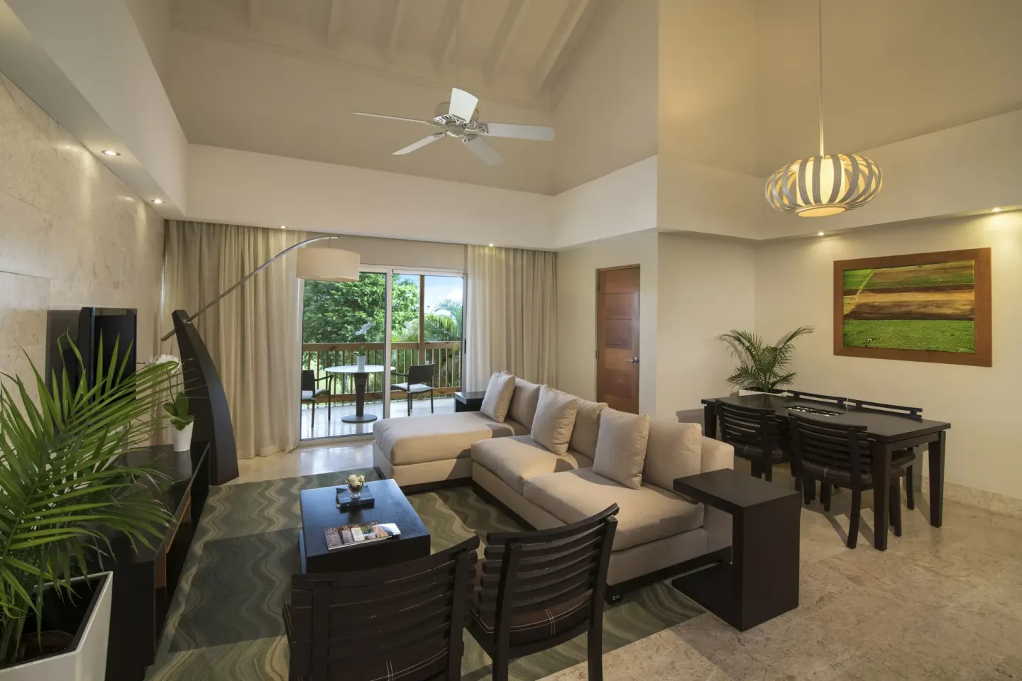 Elite Suite living room at Casa de Campo Resort and Villas with dining table and balcony doors.
