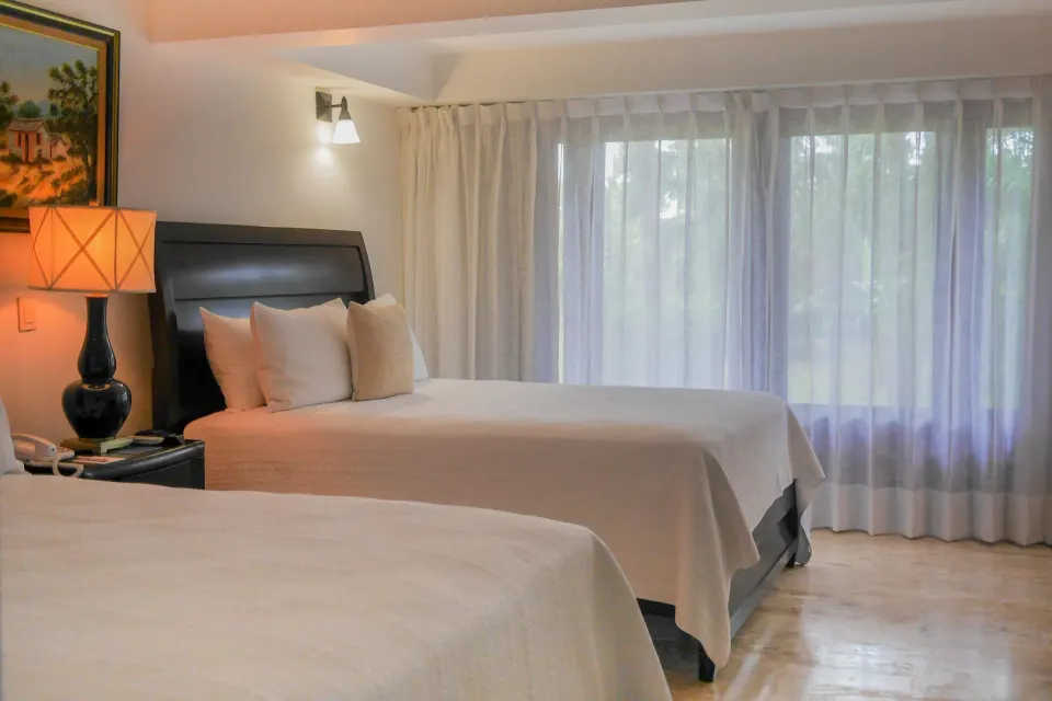 Bedroom with two beds and sheer curtains in a villa at Casa de Campo Resort and Villas.