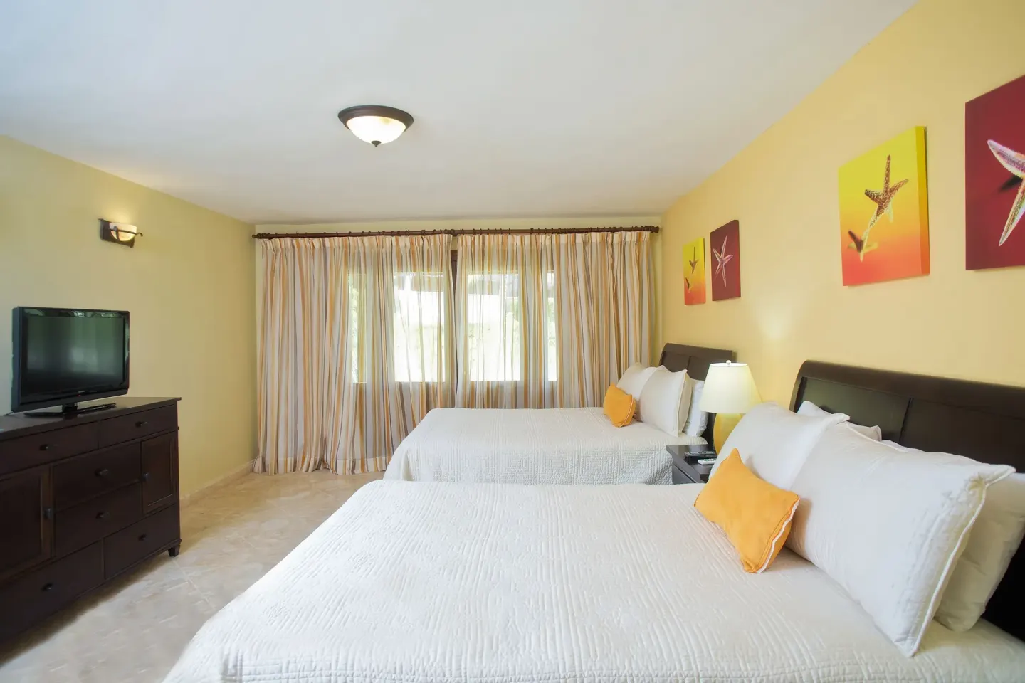 Bedroom with two beds and starfish wall art in a Five Bedroom Classic Villa at Casa de Campo Resort and Villas and Villas and Villas.