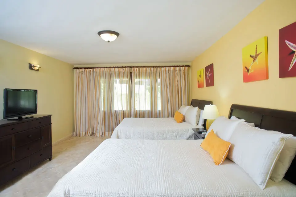 Bright bedroom with two beds and wall art in a villa at Casa de Campo Resort and Villas.