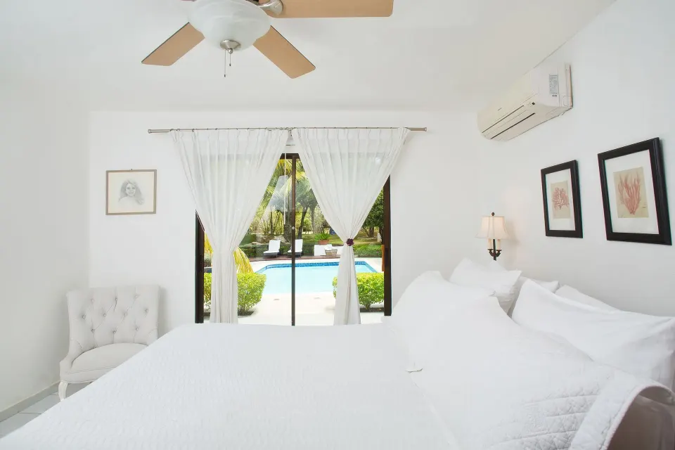 White bedroom with pool view in a Four Bedroom Garden Villa at Casa de Campo Resort and Villas.