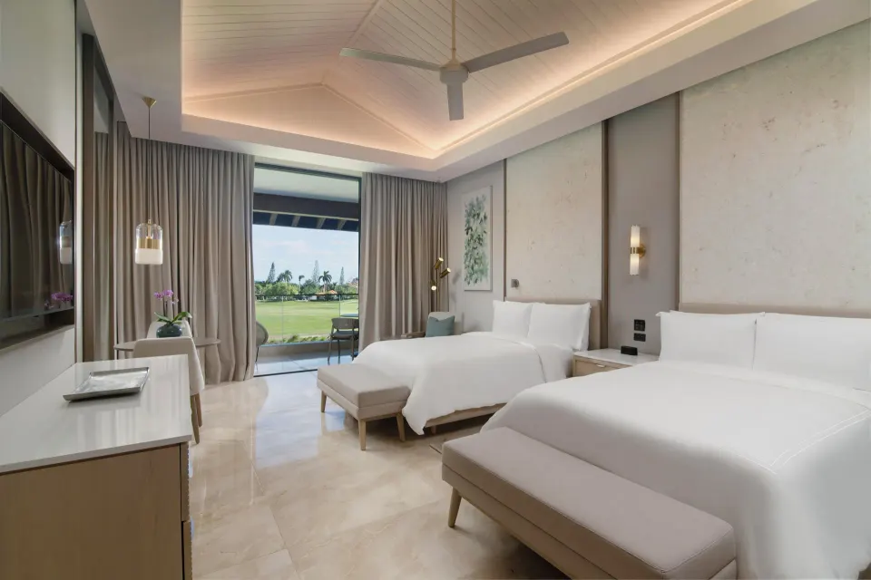 Two double beds and patio doors in a Premier Jr. Suite at Casa de Campo Resort and Villas.