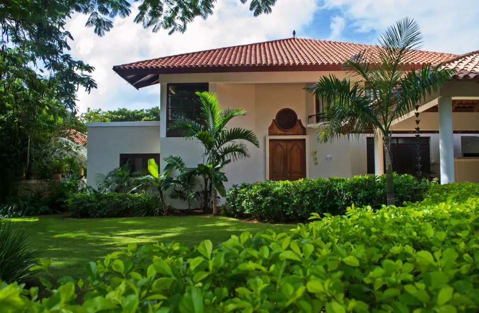Three Bedroom Garden Villa exterior framed by palms and hedges at Casa de Campo Resort and Villas.