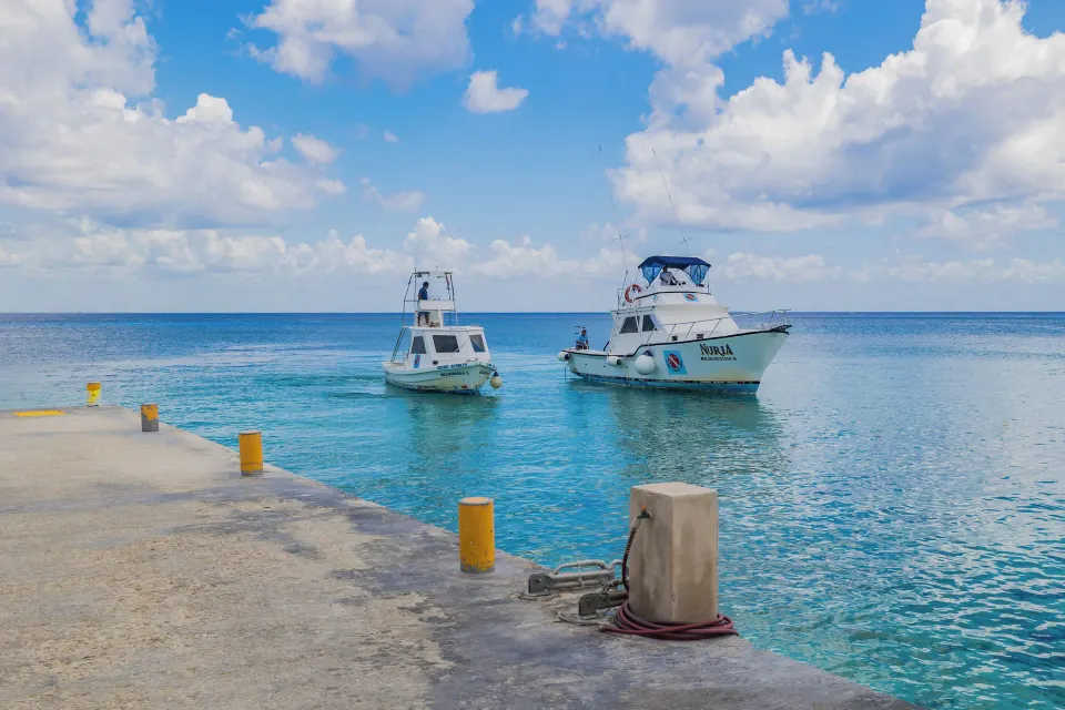 Two small boats moored beside the resort dock in calm turquoise water at Casa del Mar Cozumel Hotel & Dive Resort