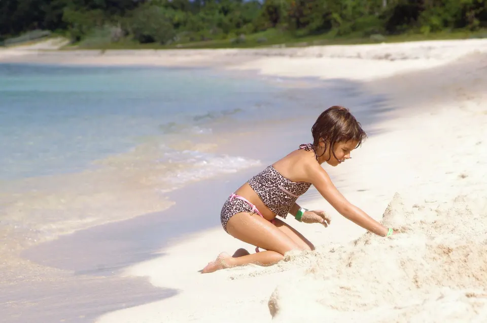 Child playing in soft sand on the beach at Casa del Mar Cozumel Hotel & Dive Resort