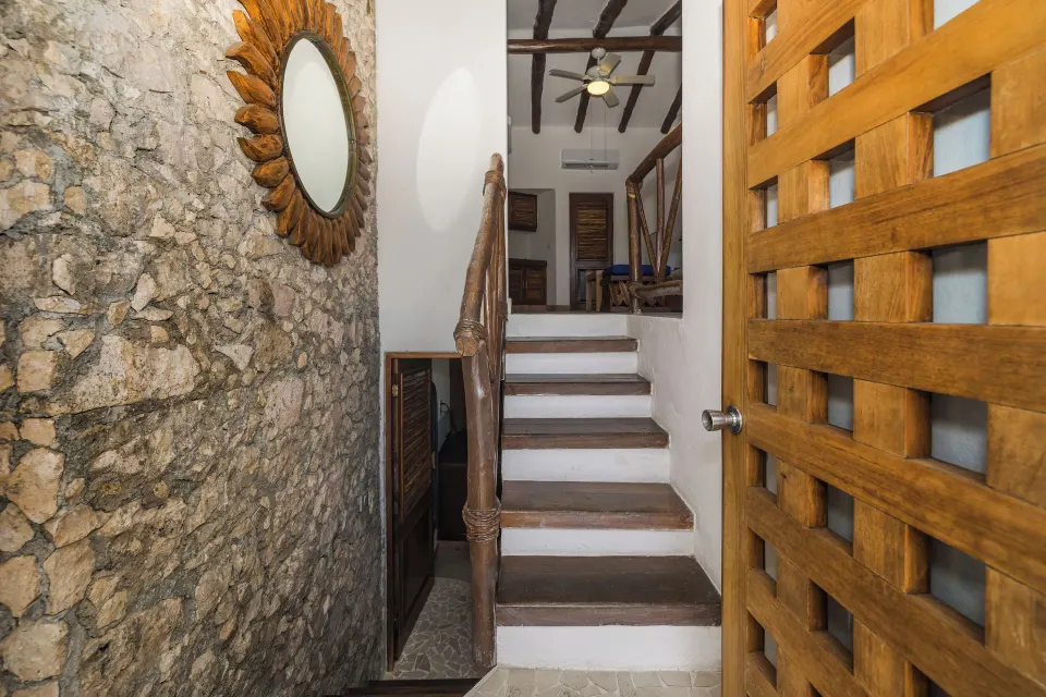 Wooden door opening to a staircase and carved stone wall at Casa del Mar Cozumel Hotel & Dive Resort
