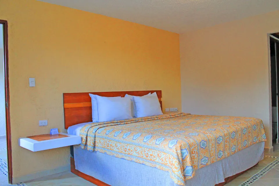 King bed with patterned coverlet in a guest room at Casa del Mar Cozumel Hotel & Dive Resort