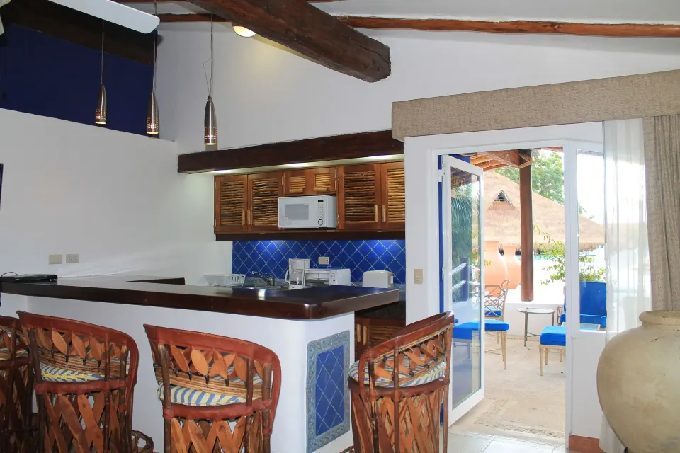 Kitchenette and breakfast bar with wicker stools opening to patio at Casa del Mar Cozumel Hotel & Dive Resort