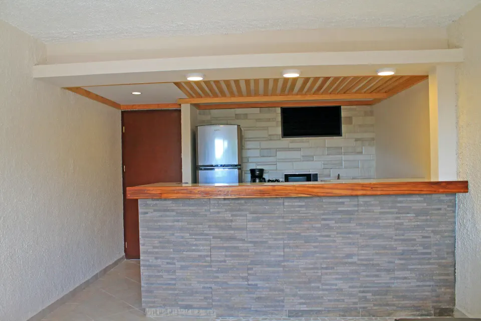 Small kitchenette counter with fridge and wall TV at Casa del Mar Cozumel Hotel & Dive Resort