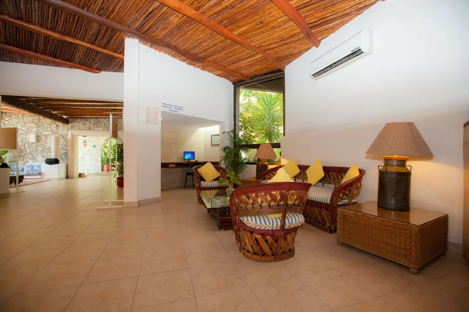 Lobby seating area with wicker chairs and thatched ceiling at Casa del Mar Cozumel Hotel & Dive Resort.