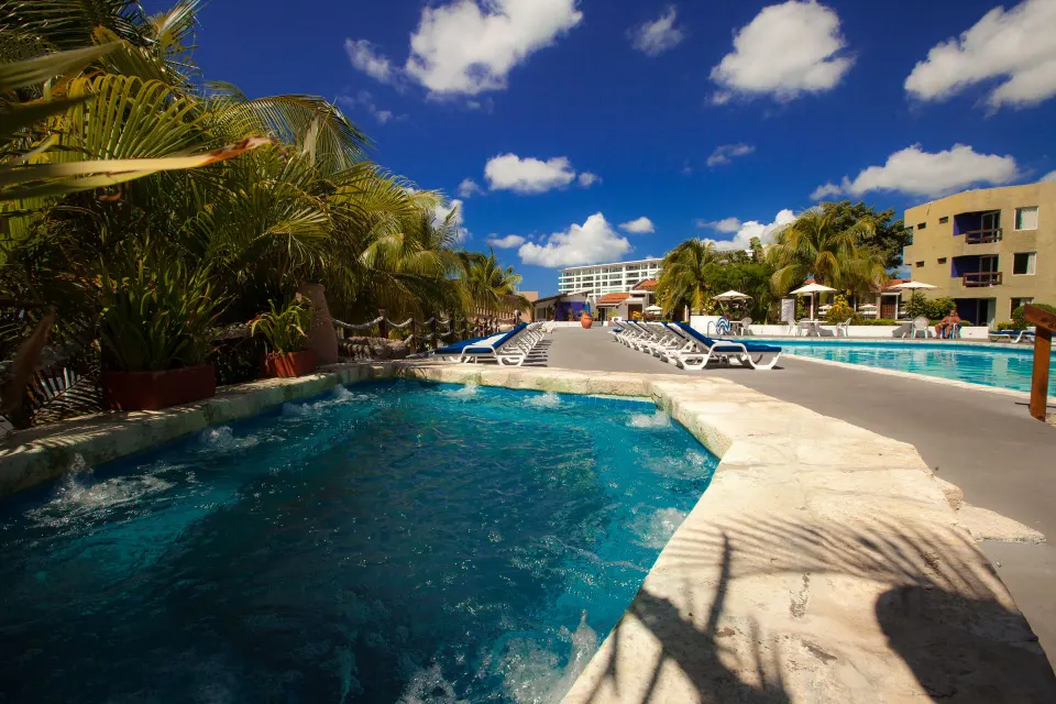 Resort pool deck with lounge chairs and palm trees at Casa del Mar Cozumel Hotel & Dive Resort