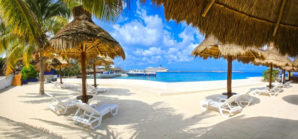 Sandy poolside beach with palapas, loungers and ocean view at Casa del Mar Cozumel Hotel & Dive Resort