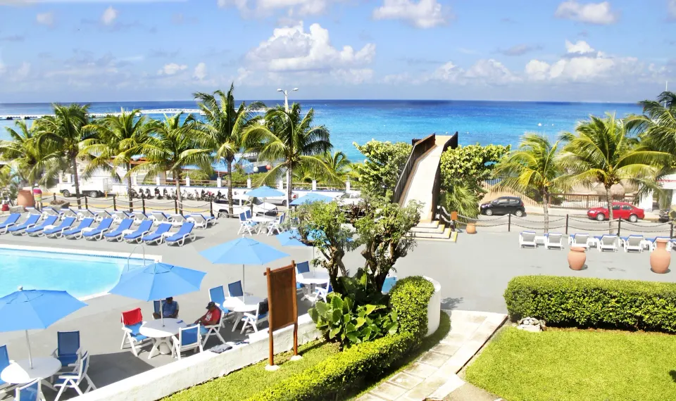 Pool terrace with loungers, palms and ocean beyond at Casa del Mar Cozumel Hotel & Dive Resort