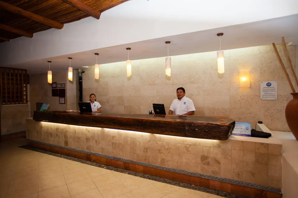 Front desk staff behind the reception counter at Casa del Mar Cozumel Hotel & Dive Resort.