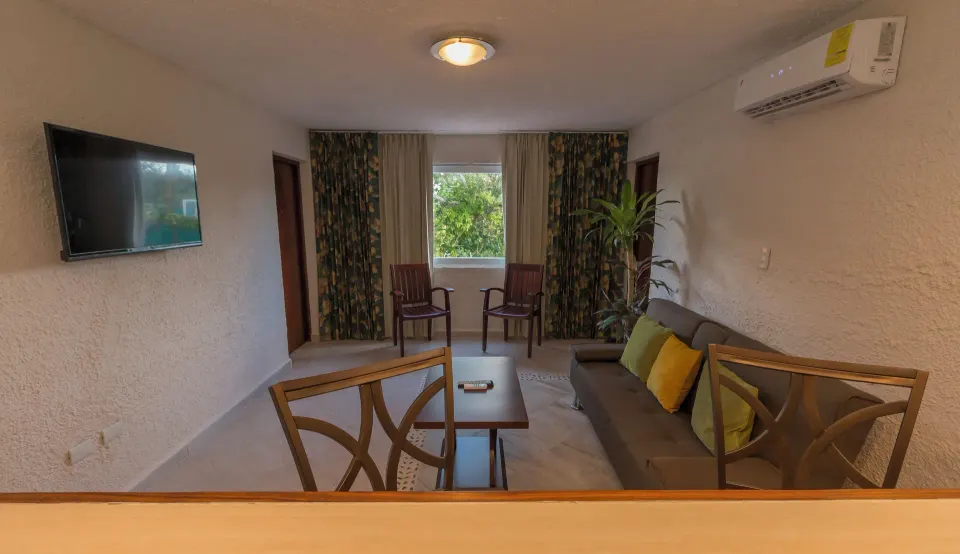 Small sitting area with sofa, TV and window view at Casa del Mar Cozumel Hotel & Dive Resort