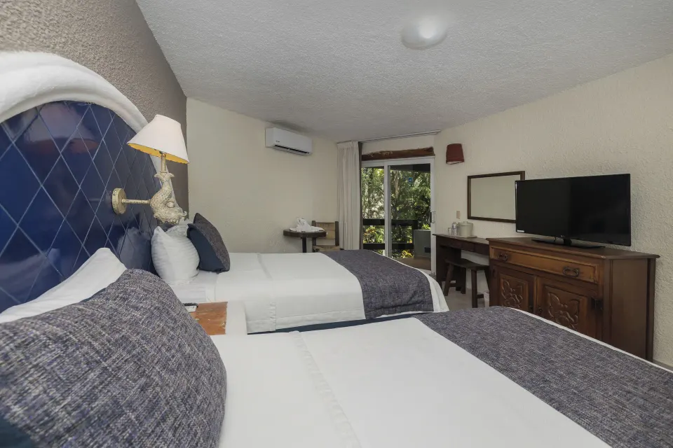 Two double beds with blue headboards in a guest room at Casa del Mar Cozumel Hotel & Dive Resort