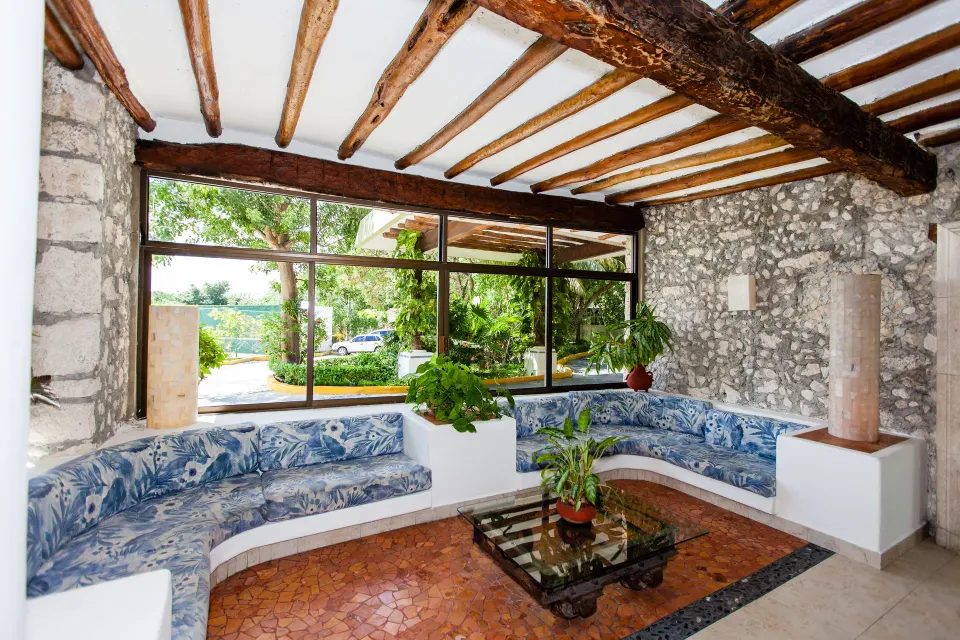 Stone-walled lobby seating with built-in curved bench and large windows at Casa del Mar Cozumel Hotel & Dive Resort.