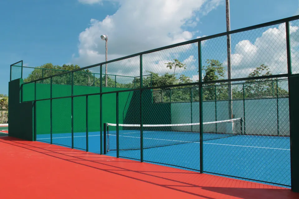 Enclosed tennis court with blue playing surface at Casa del Mar Cozumel Hotel & Dive Resort
