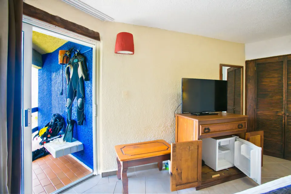 Room TV cabinet and open balcony area with dive gear hanging at Casa del Mar Cozumel Hotel & Dive Resort
