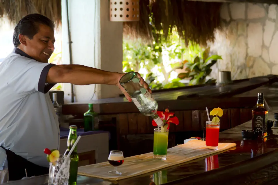 Bartender pouring colorful cocktails at Casa del Mar Cozumel Hotel & Dive Resort bar