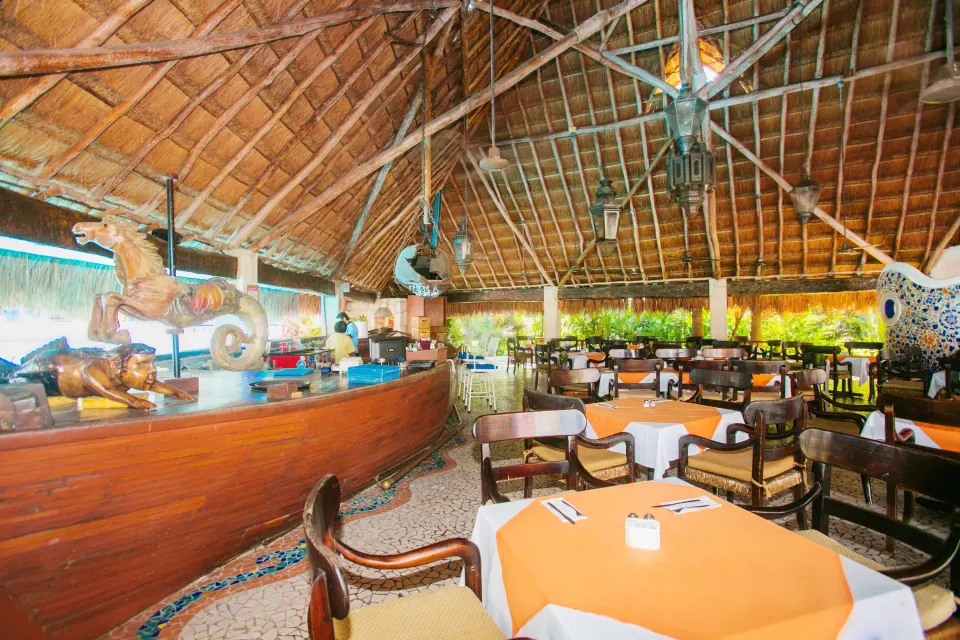 Open-air palapa restaurant dining area with wooden chairs and table settings at Casa del Mar Cozumel Hotel & Dive Resort