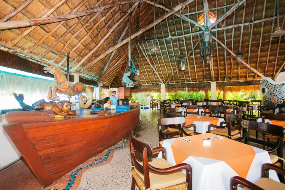 Palapa restaurant with wooden boat-style bar at Casa del Mar Cozumel Hotel & Dive Resort